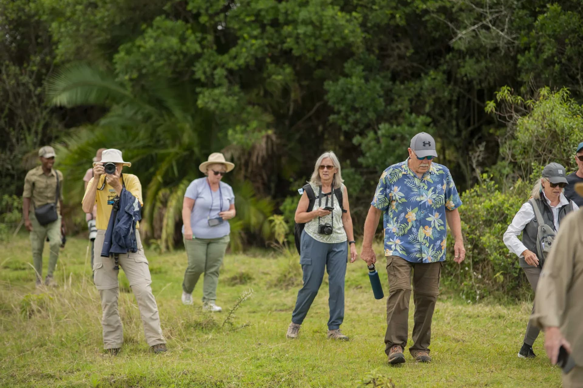 A group of senior travelers walking together with cameras on a Tanzania safari