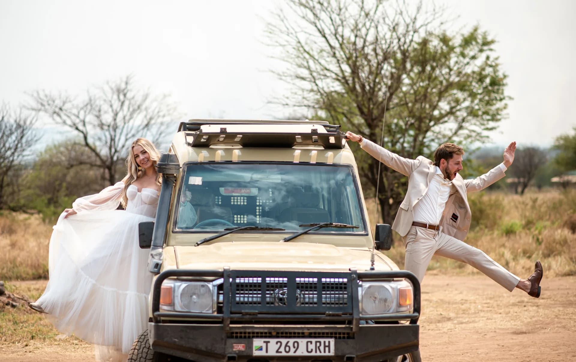 Newlyweds celebrating in front of a safari vehicle after their bush wedding ceremony